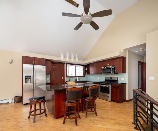 kitchen featuring a center island, baseboard heating, light wood-style flooring, a kitchen breakfast bar, and stainless steel appliances