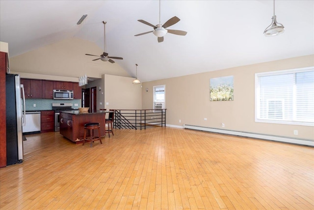 kitchen featuring a breakfast bar, dark countertops, light wood-style floors, and appliances with stainless steel finishes