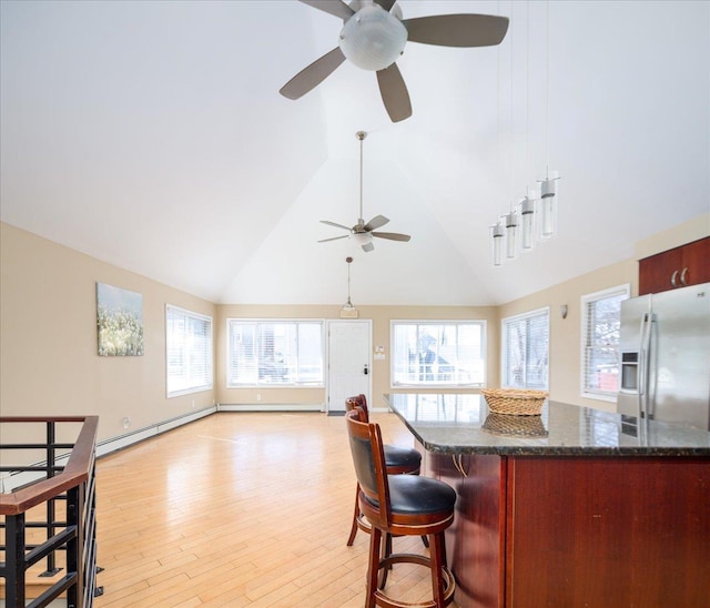 kitchen featuring a kitchen bar, light wood-style floors, white fridge with ice dispenser, and a wealth of natural light