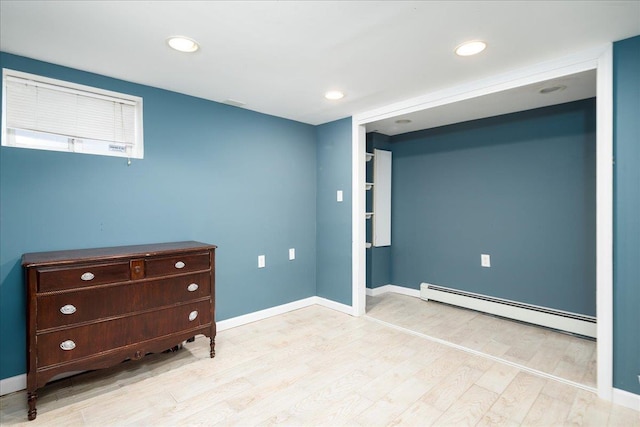 interior space with a baseboard heating unit, recessed lighting, wood finished floors, and baseboards