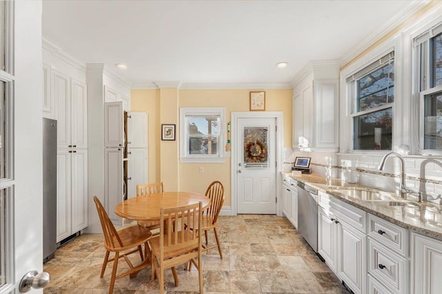 kitchen with a sink, appliances with stainless steel finishes, white cabinetry, crown molding, and tasteful backsplash