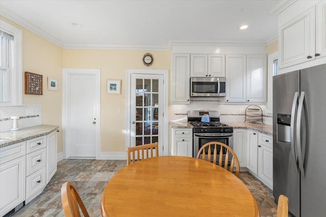 kitchen with tasteful backsplash, crown molding, baseboards, stainless steel appliances, and white cabinetry