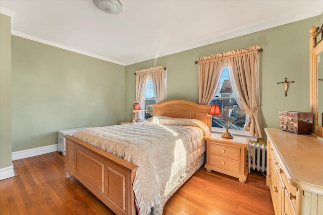 bedroom featuring hardwood / wood-style flooring, radiator heating unit, crown molding, and baseboards