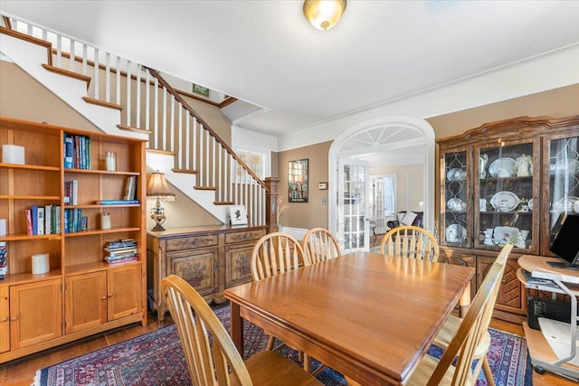 dining space featuring stairs, crown molding, and wood finished floors