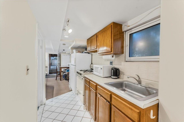 kitchen with a sink, white appliances, brown cabinetry, light countertops, and decorative backsplash