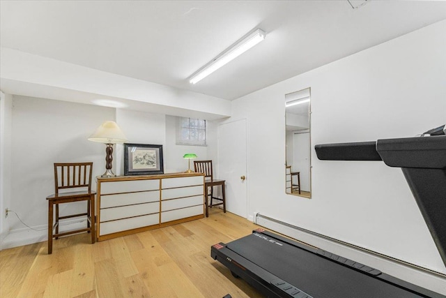 workout room with light wood-style flooring and a baseboard radiator