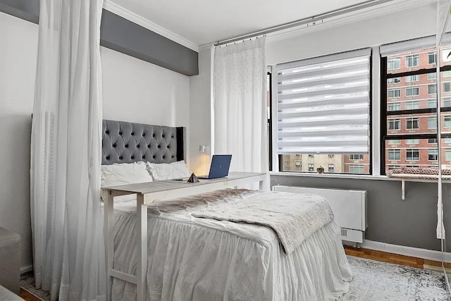 bedroom with baseboards, radiator, and crown molding