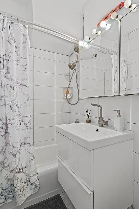 full bath featuring vanity, tile walls, and shower / bath combo