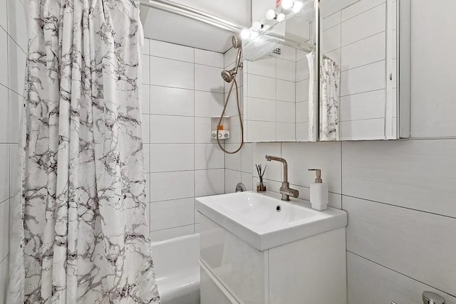 bathroom featuring tasteful backsplash, tile walls, shower / bath combo, and vanity