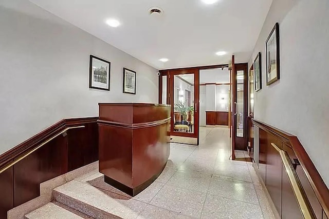 corridor featuring recessed lighting, wainscoting, and light speckled floor