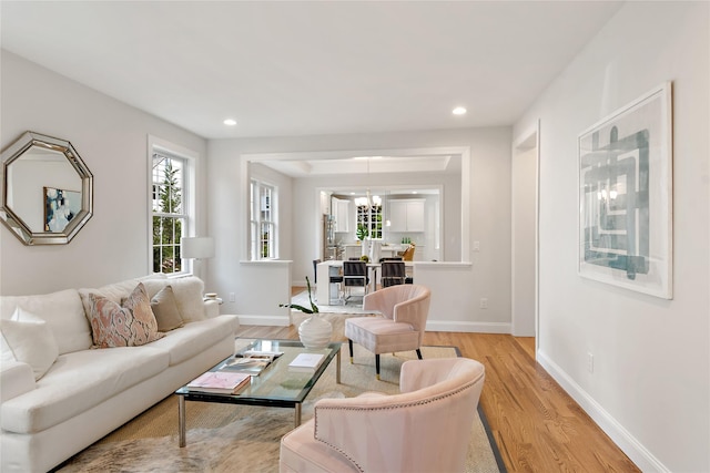 living room featuring recessed lighting, baseboards, an inviting chandelier, and light wood finished floors