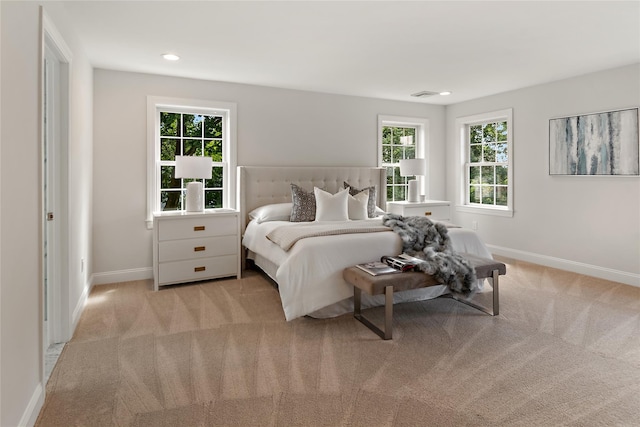 bedroom featuring light carpet, multiple windows, and baseboards