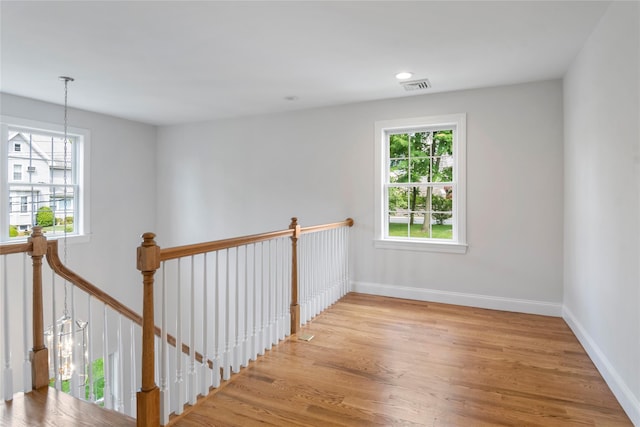 interior space with wood finished floors, a healthy amount of sunlight, visible vents, and baseboards