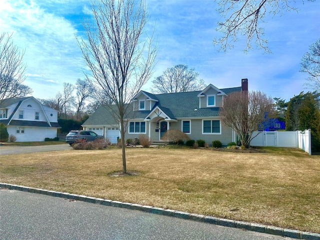 view of front facade featuring fence, roof with shingles, a front yard, a garage, and a chimney