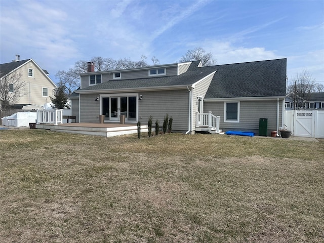 back of house featuring a gate, fence, a yard, a shingled roof, and a wooden deck