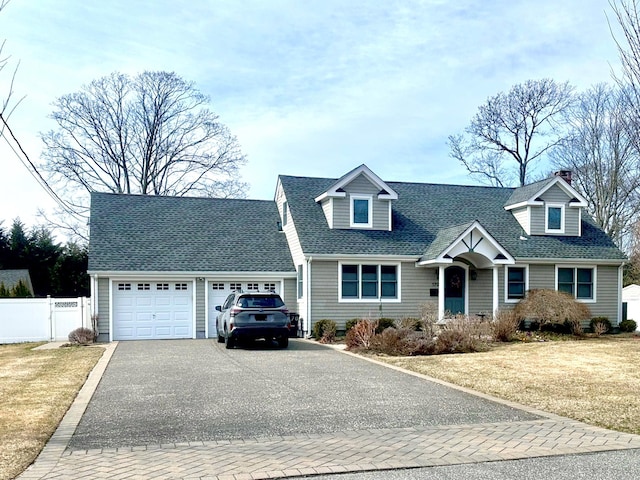 cape cod house with a front yard, fence, driveway, roof with shingles, and an attached garage