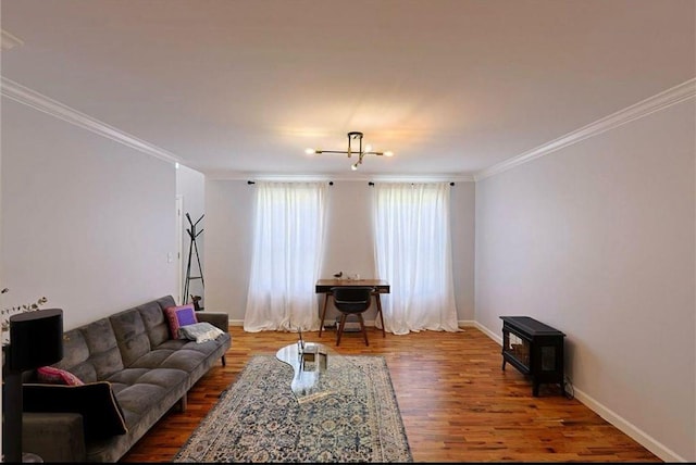 living area featuring crown molding, a wood stove, wood finished floors, and baseboards