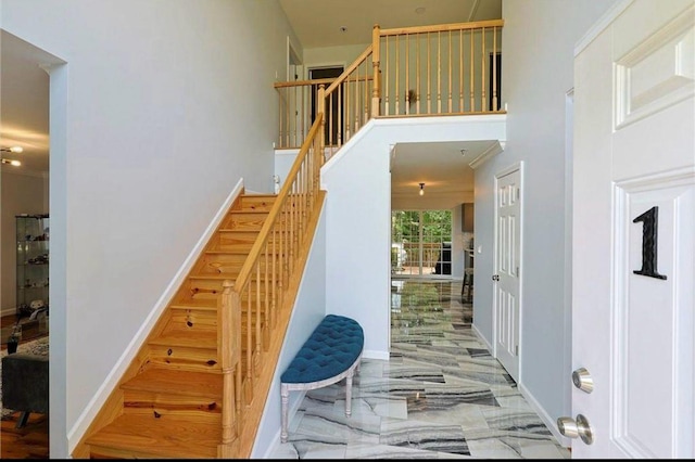 staircase featuring marble finish floor, baseboards, and a towering ceiling