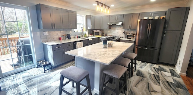 164 Lake Shore Dr E, Rock Hill, NY 12775 - kitchen with stainless steel appliances, under cabinet range hood, gray cabinetry, a breakfast bar area, and crown molding
