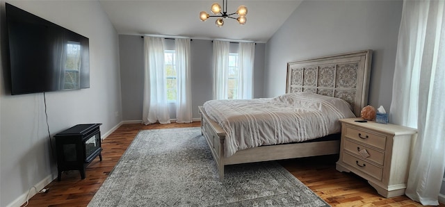 164 Lake Shore Dr E, Rock Hill, NY 12775 - bedroom with vaulted ceiling, a chandelier, a wood stove, and wood finished floors