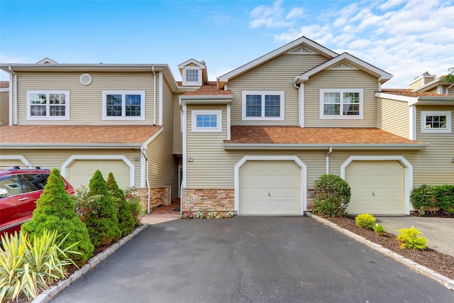 multi unit property featuring aphalt driveway, stone siding, a shingled roof, and a garage