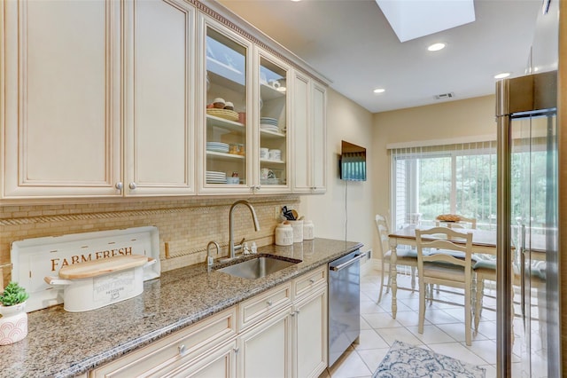 kitchen featuring visible vents, a skylight, a sink, decorative backsplash, and dishwasher