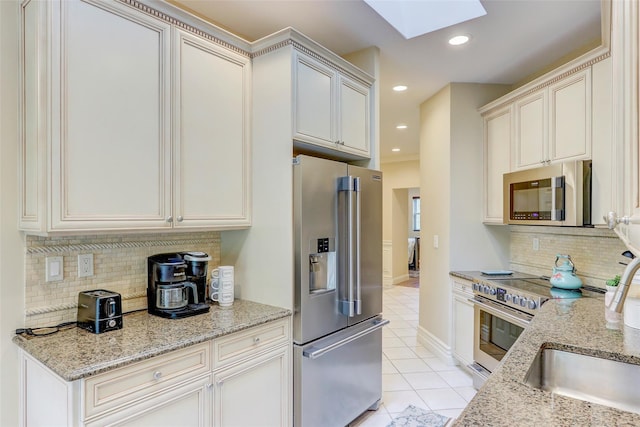 kitchen with light stone counters, light tile patterned floors, a skylight, recessed lighting, and stainless steel appliances