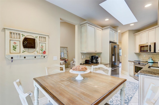 dining area featuring a skylight, light tile patterned floors, recessed lighting, and baseboards