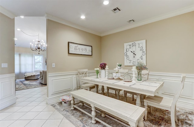 dining room with visible vents, a wainscoted wall, ornamental molding, light tile patterned floors, and an inviting chandelier