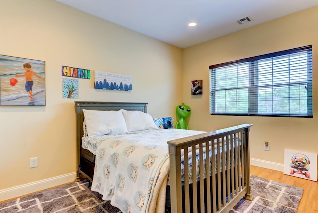 bedroom with recessed lighting, visible vents, baseboards, and wood finished floors