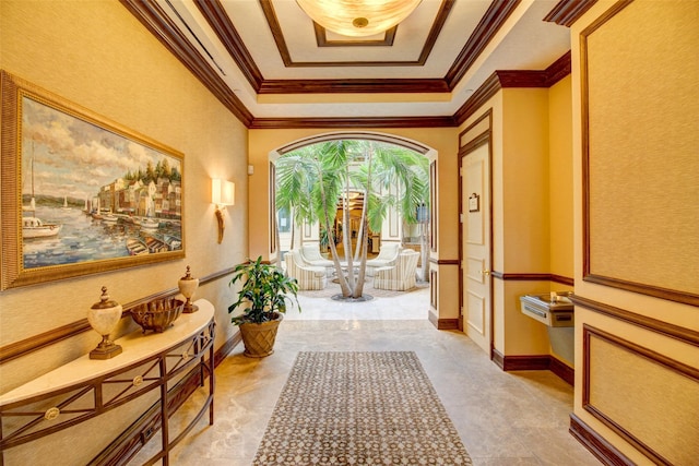 corridor with a raised ceiling, baseboards, and ornamental molding