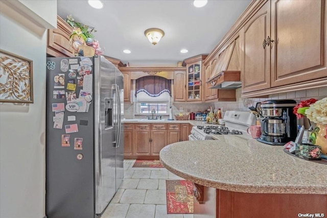 kitchen with a peninsula, gas range gas stove, glass insert cabinets, stainless steel refrigerator with ice dispenser, and backsplash