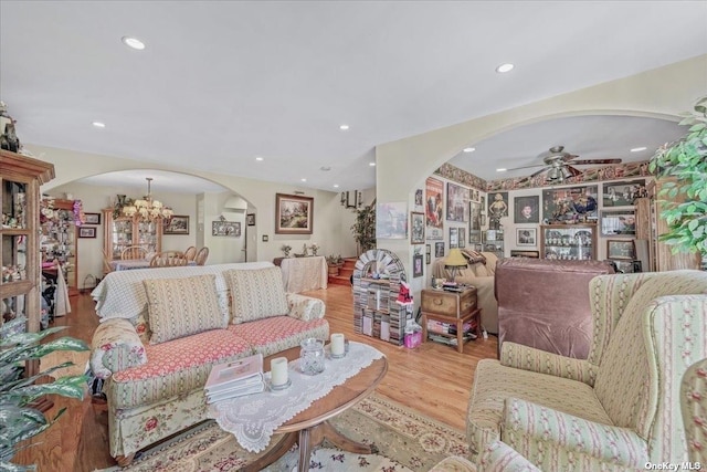 living room with ceiling fan with notable chandelier, recessed lighting, wood finished floors, and arched walkways