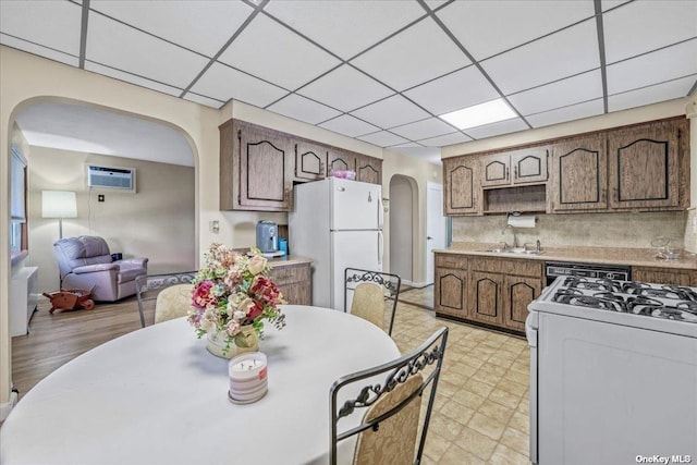 kitchen with white appliances, arched walkways, a sink, light countertops, and tasteful backsplash