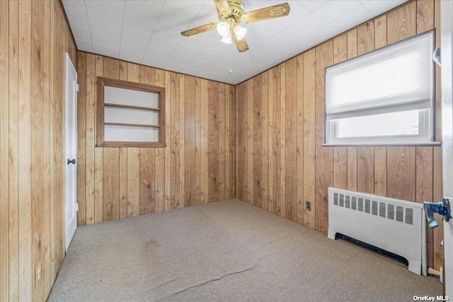 empty room with wooden walls, radiator, and carpet floors