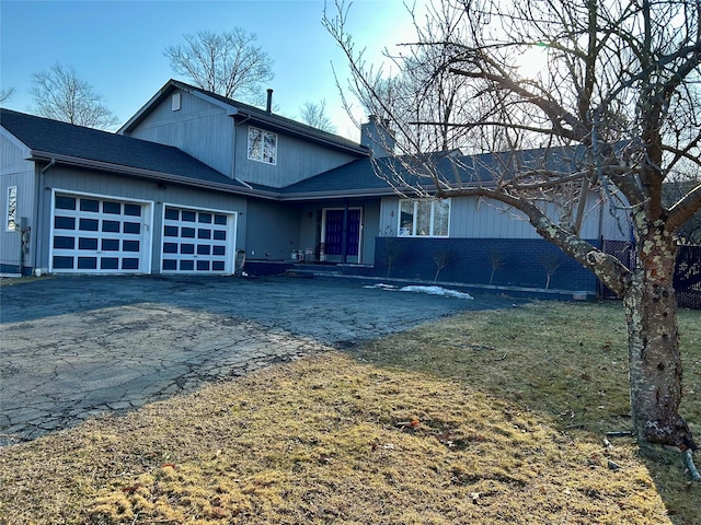 view of front of home featuring aphalt driveway, a chimney, and a garage