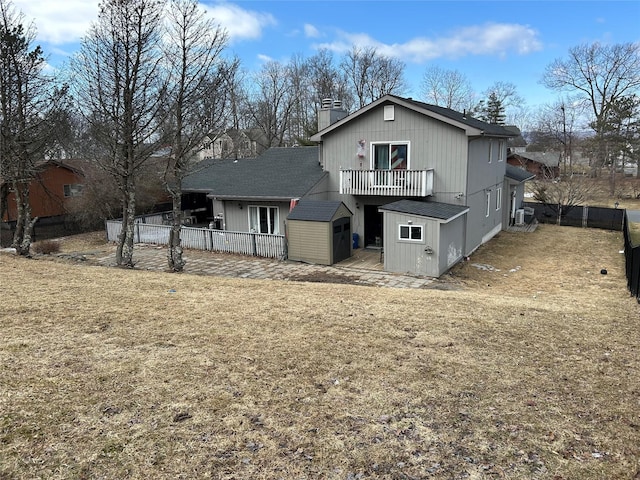 back of house featuring an outbuilding, a storage shed, a chimney, and fence