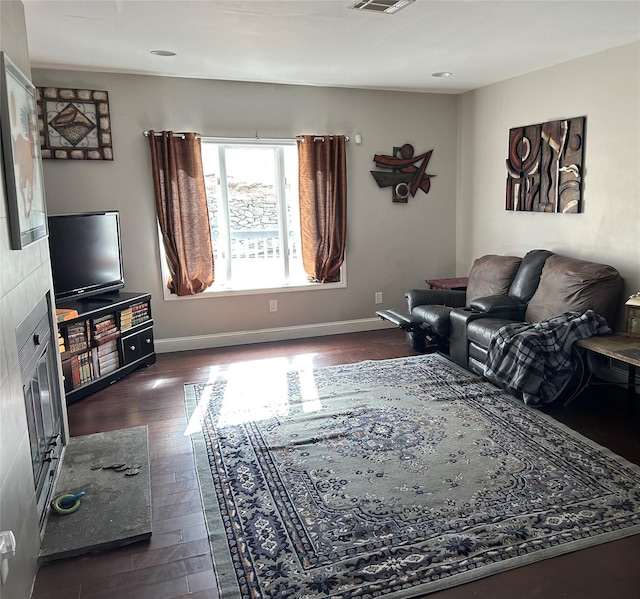 living room with visible vents, baseboards, and dark wood finished floors