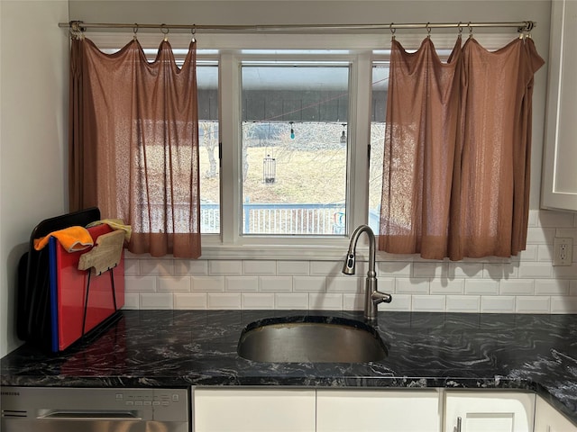 kitchen featuring a sink, tasteful backsplash, stainless steel dishwasher, and white cabinetry