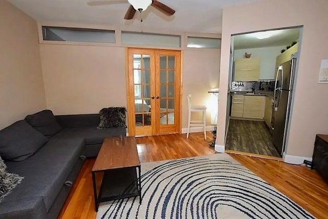 living area featuring french doors, a ceiling fan, and wood finished floors