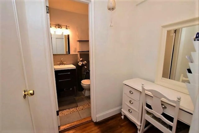 bathroom featuring toilet, vanity, baseboards, and wood finished floors