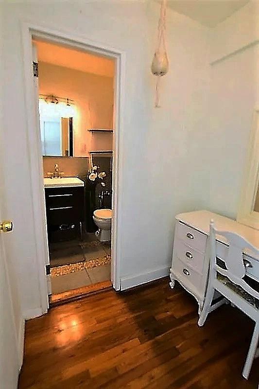 bathroom featuring baseboards, toilet, wood finished floors, and vanity