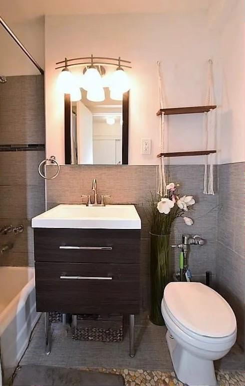 bathroom with vanity, tile walls, toilet, and shower / bathing tub combination