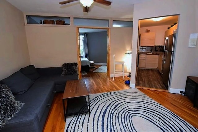 living area featuring baseboards, wood finished floors, and a ceiling fan