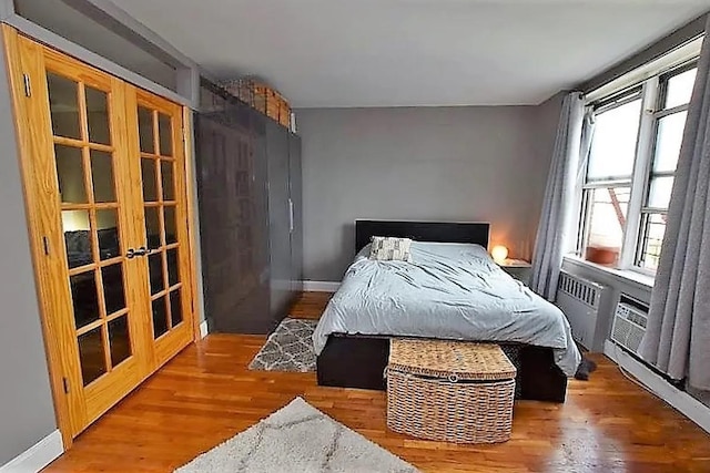 bedroom with french doors, baseboards, and wood finished floors