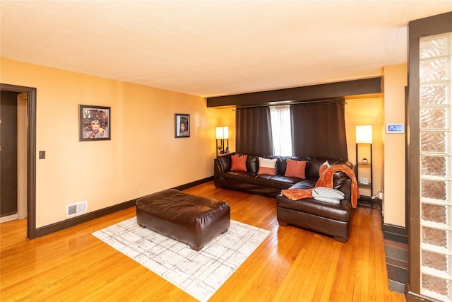 living room with light wood finished floors, visible vents, and baseboards