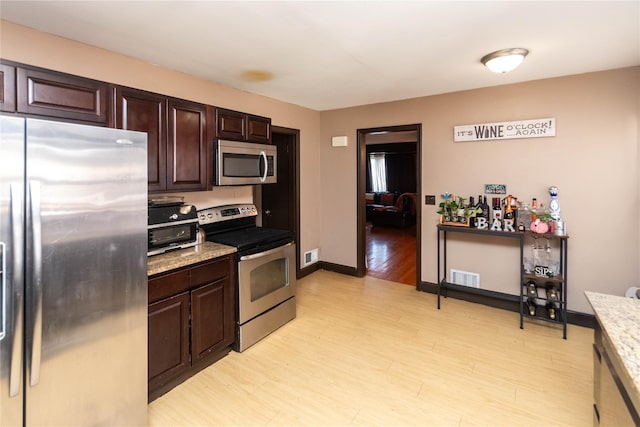 kitchen featuring light wood-type flooring, stainless steel appliances, dark brown cabinetry, and visible vents