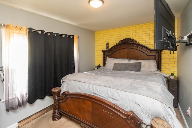 bedroom featuring multiple windows, baseboards, and brick wall