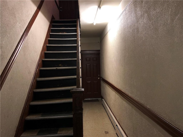 staircase with a baseboard radiator and a textured wall