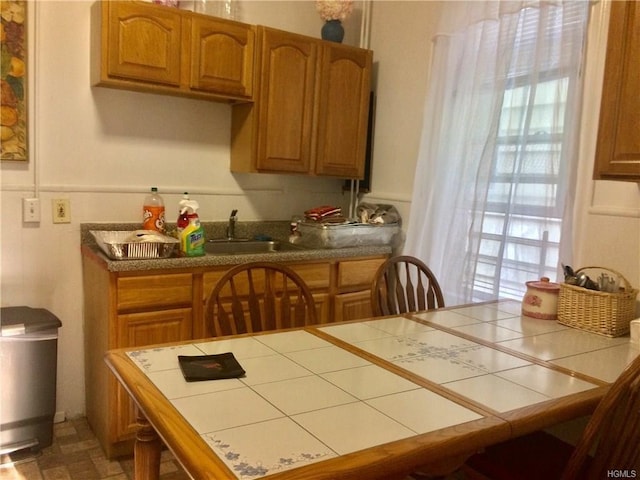 kitchen with a sink, brown cabinetry, and tile countertops